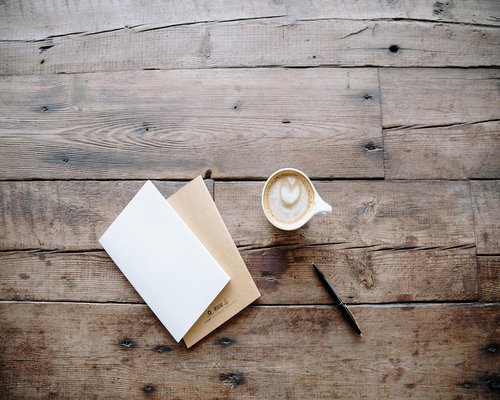 Café, libreta y lentes sobre un escritorio luminoso